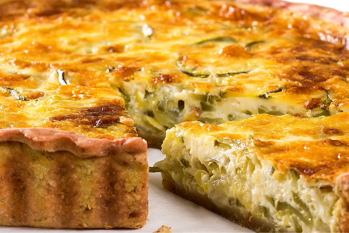 Coronation Quiche garnished with fresh herbs on a white plate