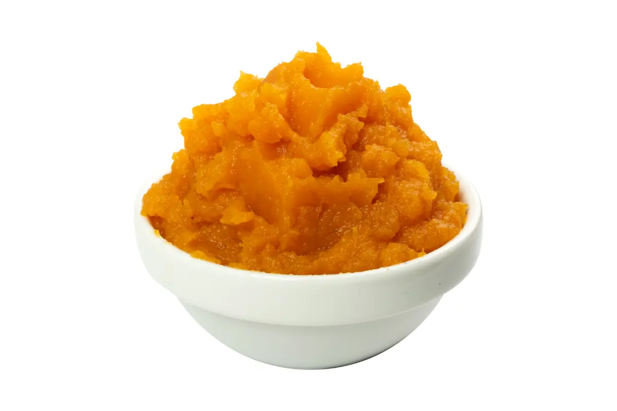 A bowl of mashed sweet potato mixture, ready for pie filling, on a white background
